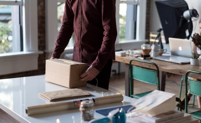 A parcel being packed and taped on a workbench in a bright fulfillment studio