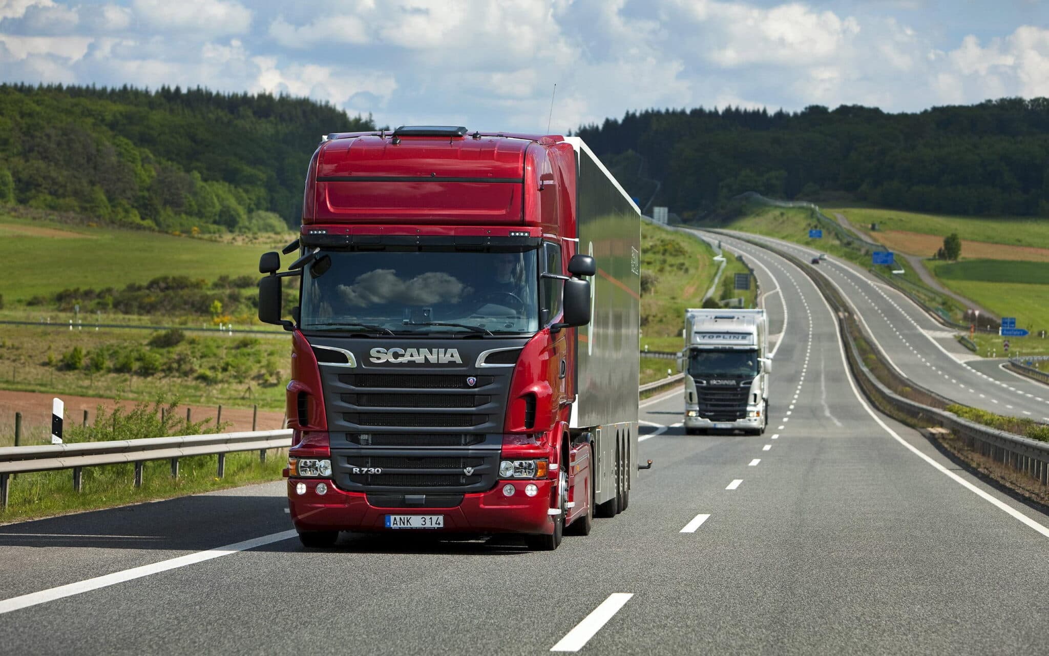 Freight trucks travelling on an open motorway through green countryside